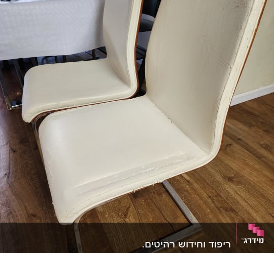 כיסאות מרופדים בלבן עם רגלי מתכת על רצפת עץ